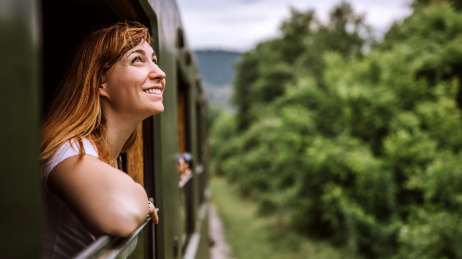 female-tourist-traveling-in-train-standing-out-of-window-train-and-looking-beautiful-nature-stockpack-istock.jpg